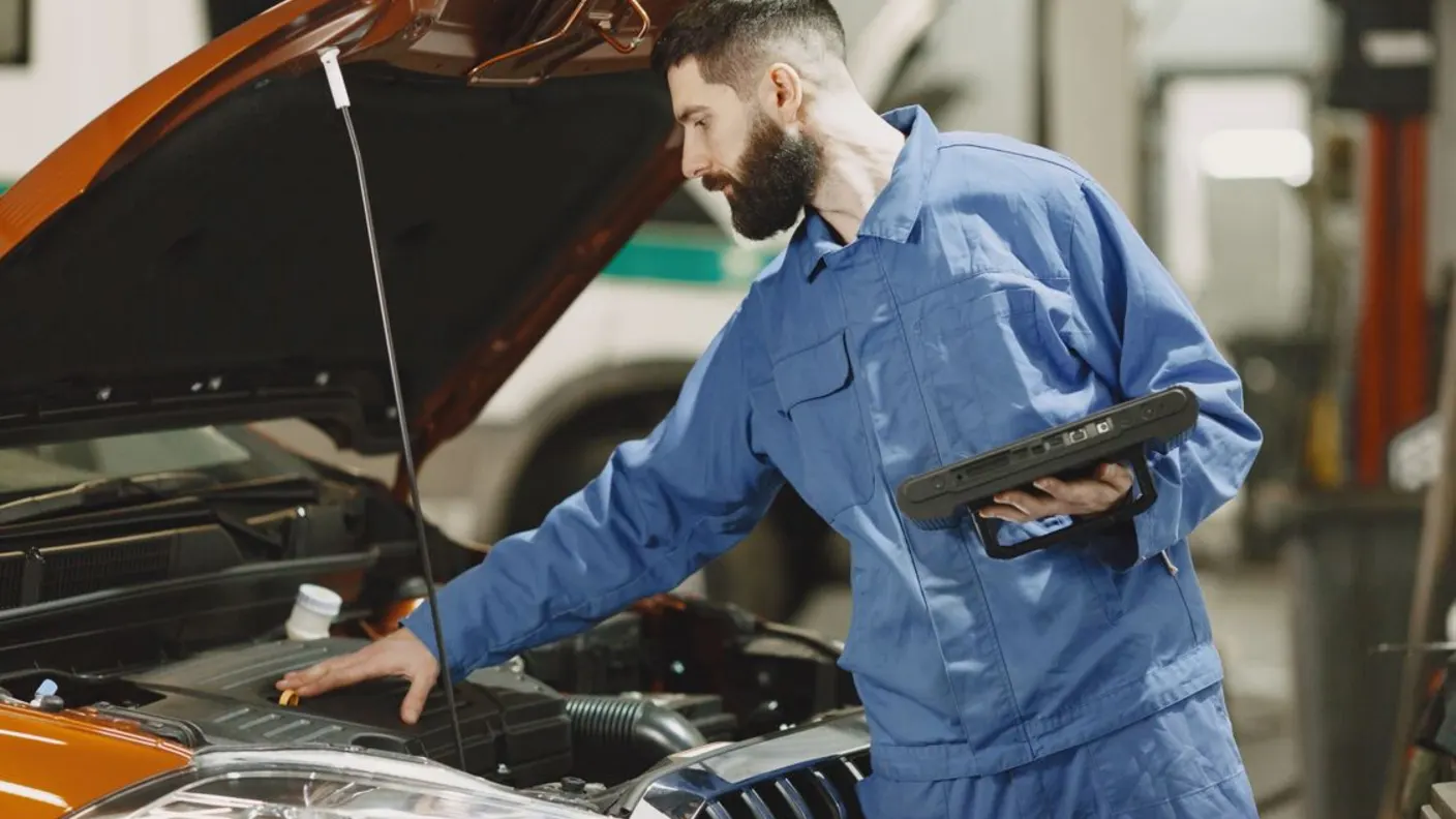 Kfz-Fachmann inspiziert den geöffneten Motorraum eines Fahrzeugs bei einer Werkstattdiagnose